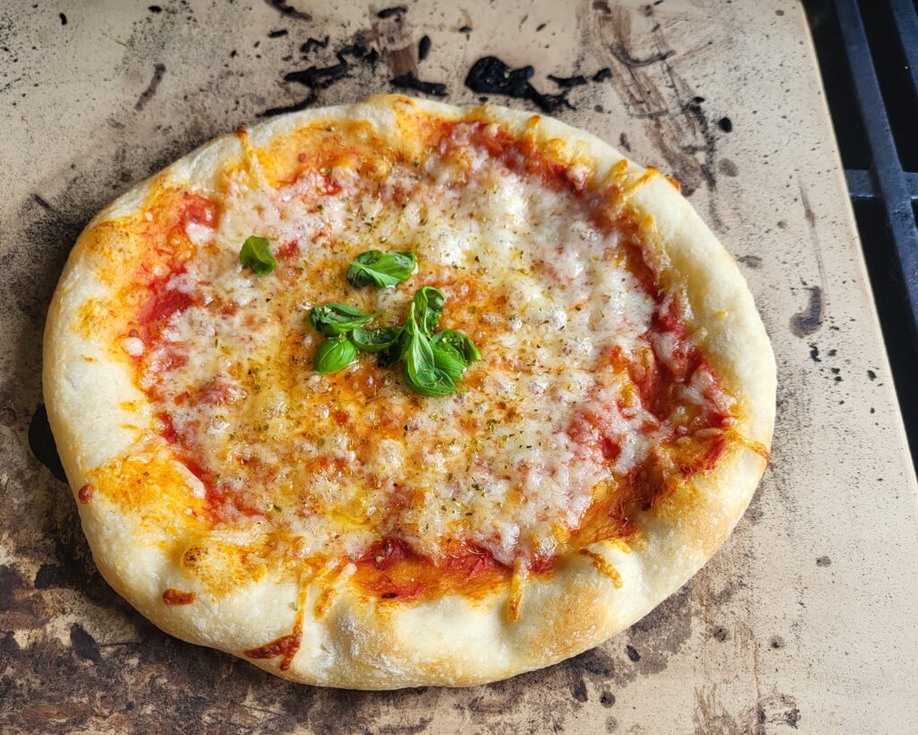 Eine fertige Pizza Margherita auf dem Pizzastein. 